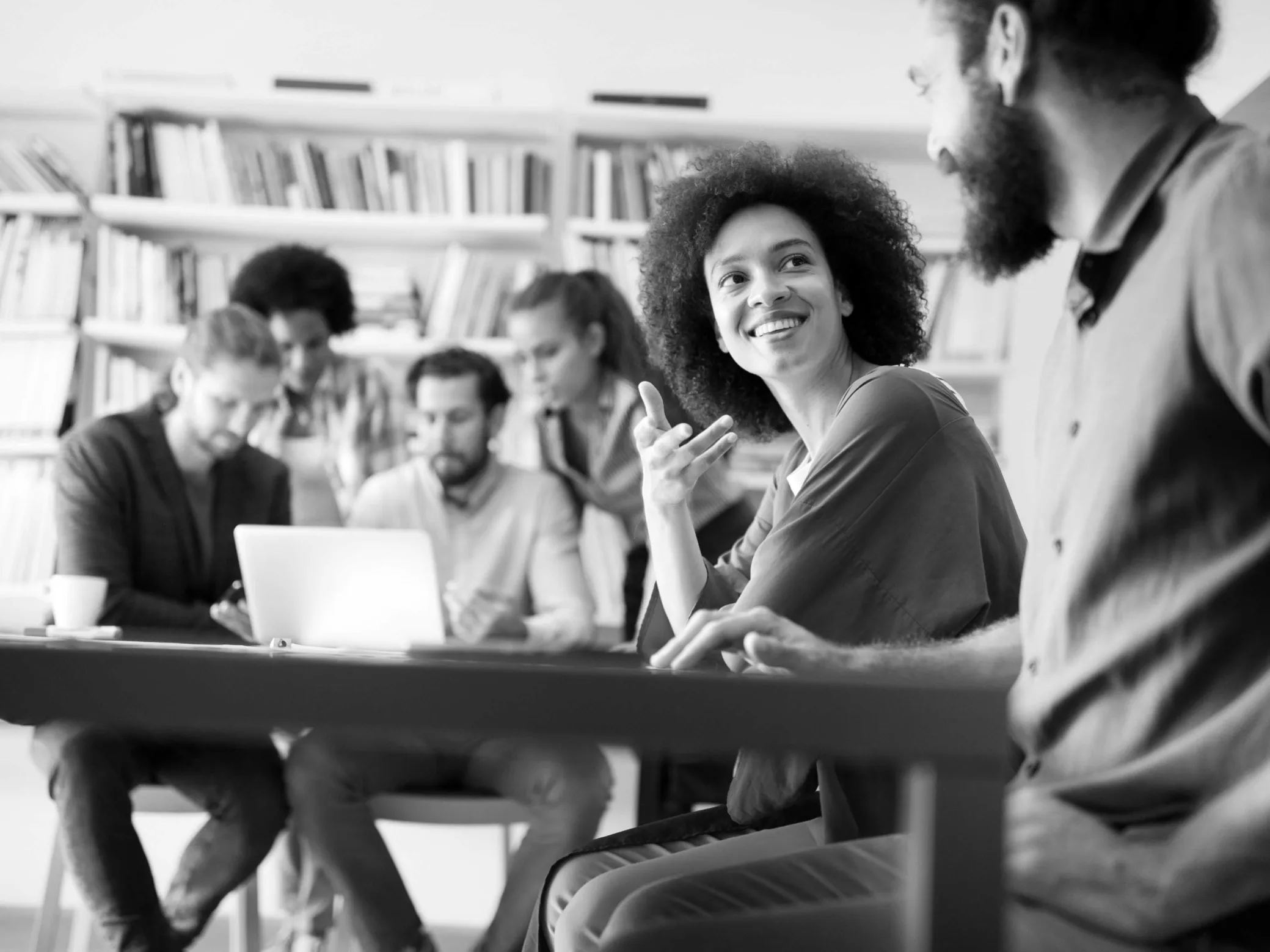 Diverse group of young professionals collaborating around a laptop in a modern office setting.